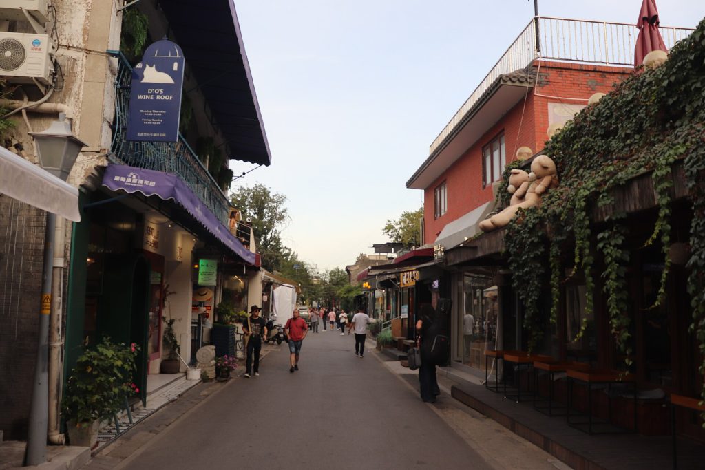 A quieter stretch of Wudaoying Hutong lined with trees and low-rise buildings.