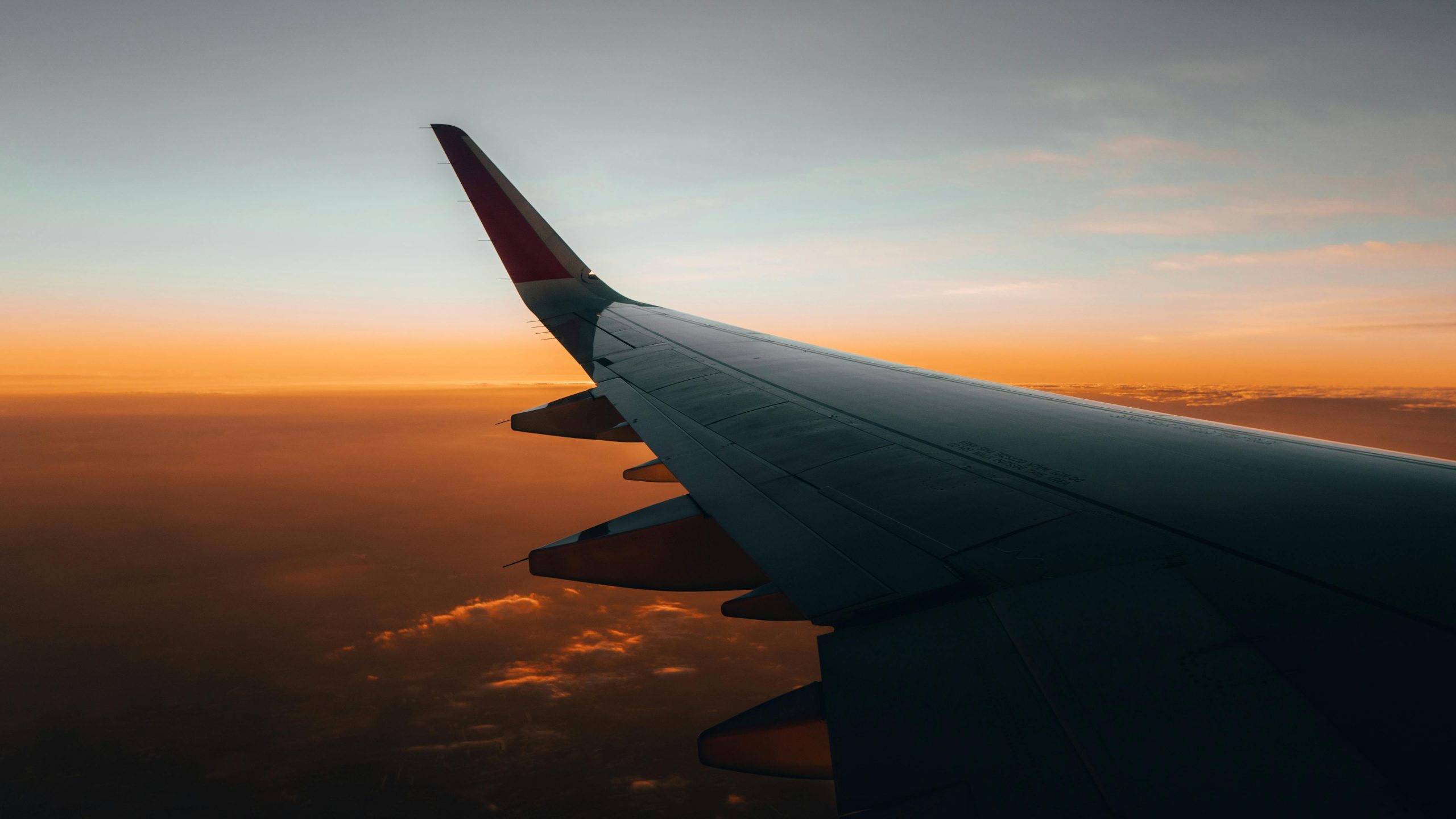 Airplane wing against a dawn sky over illuminated clouds