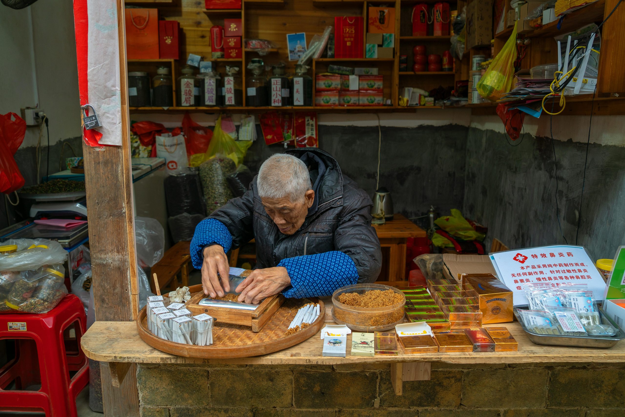 Elderly man preparing tea at a traditional Chinese tea shop counter