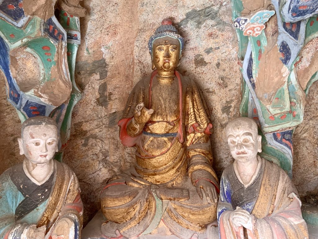 Buddhist sculptures inside the Hanging Temple, with gilded figures set into the cliff-face wall